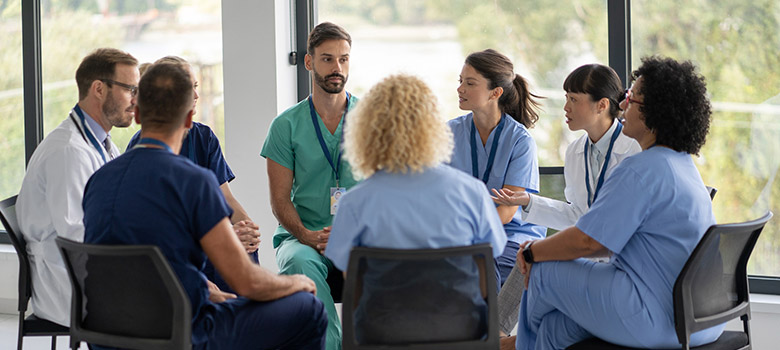 Un groupe de soignants discutent. Ils sont assis en cercle dans une salle lumineuse de l'hôpital - La Prévention Médicale