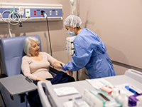 Une infirmière pose une perfusion de chimiothérapie à une femme âgée - La Prévention Médicale