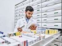Un pharmacien prend des médicaments dans le tiroir en examinant l'ordonnance - La Prévention Médicale